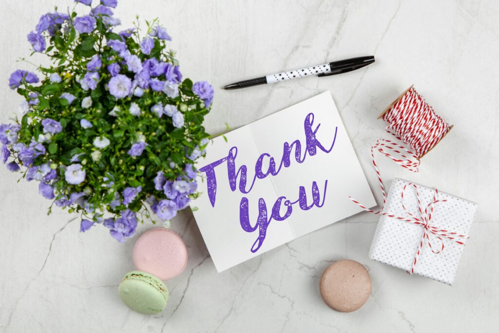 An elegant thank you card with flowers and a gift on a marble surface, perfect for expressing gratitude.