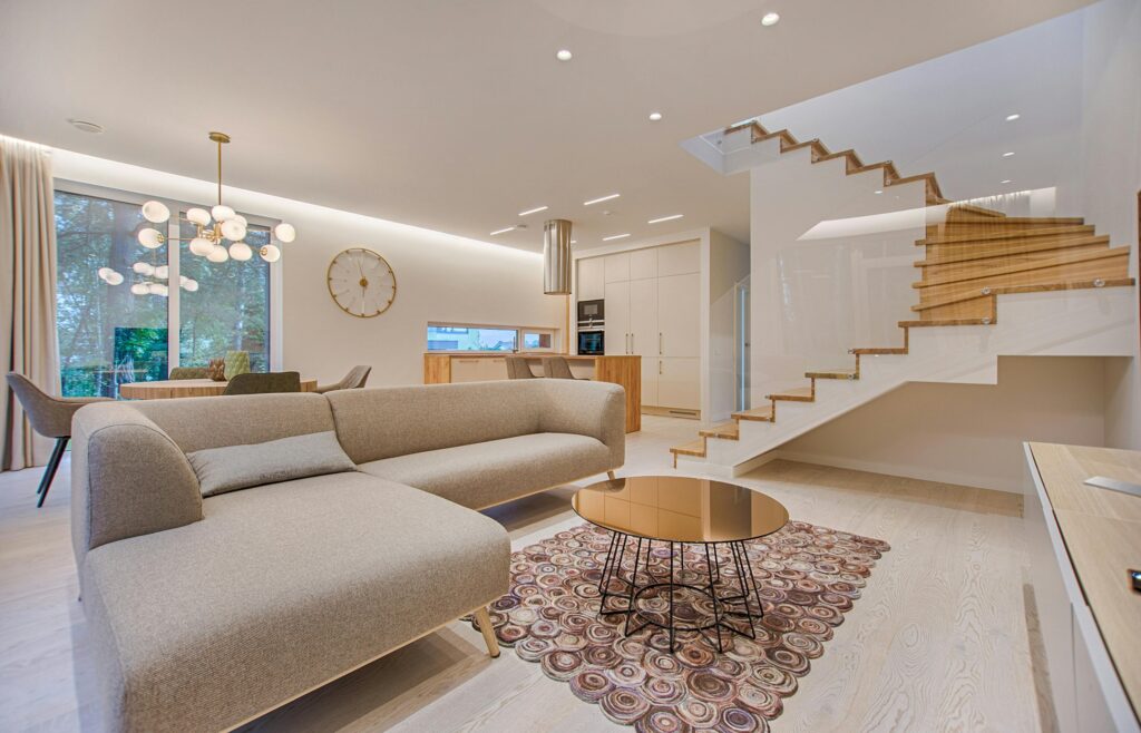 modern style living room with sofa, centre table, staircase, decorations, lighting