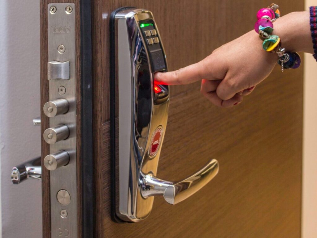 A hand using fingerprint access on a digital security door lock, enhancing safety.